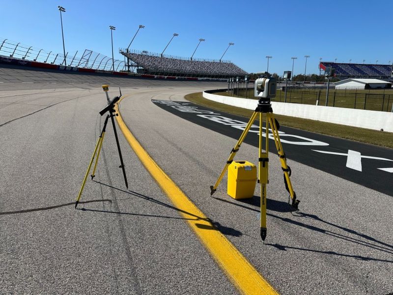 Trimble scanning total station on a tripod set up on the asphalt track at Darlington Raceway under a blue sky